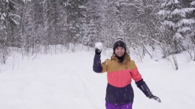 Mutlu kadın parlak kış giysileri içinde kartopu kış ormanda atar..
