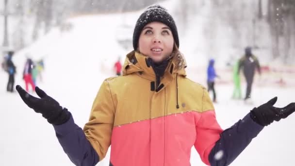 Glad tjej i skidorten med armarna upp medan det snöar — Stockvideo