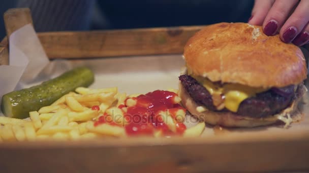 Stekt potatis marker med stora burger lekmanna-på trä servern. Burger är beredd att vara eated. Snabbmat, skräpmat koncept. — Stockvideo