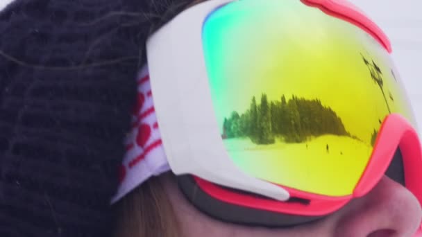 Горы и люди, катающиеся на лыжах и сноуборде отражены в лыжной маске освещенной солнечной вспышки — стоковое видео