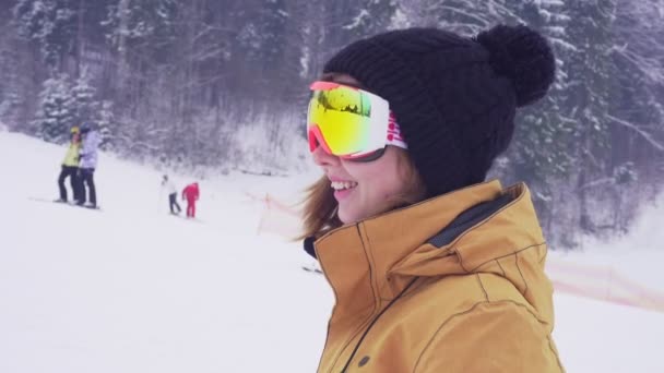 Joven mujer deportiva en gafas de esquí sonriendo y saludando con la mano . — Vídeos de Stock