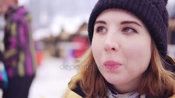 Mooie blonde eet potato chips tegen de achtergrond van de winter markt — Stockvideo