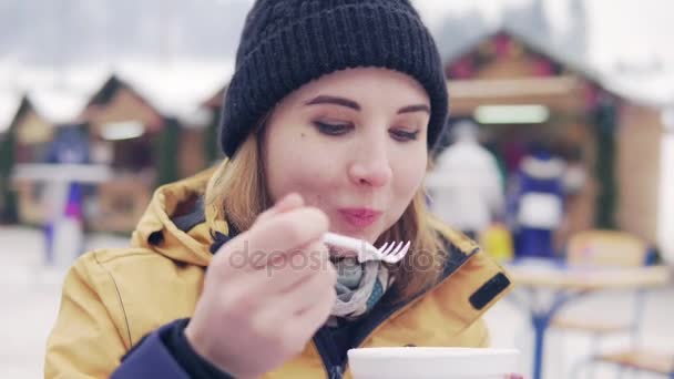 美丽的金发女郎吃 pilav 背景的冬季市场 — 图库视频影像