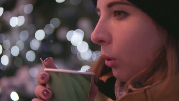 Mujer joven con té caliente está soplando en su taza de pie cerca del árbol de Navidad. Cumplimiento del concepto de deseos — Vídeo de stock