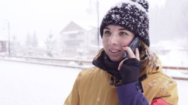 Yoğun kar yağışı ise parlak kış giysileri içinde genç kadın dışında telefonda konuşuyor