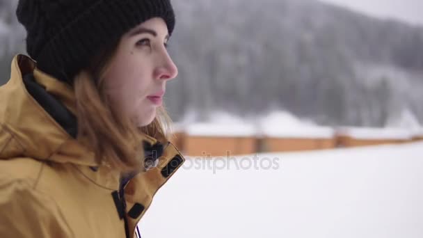 Profil rapproché de la jeune femme marchant dans la station de ski d'hiver pendant la chute de neige — Video