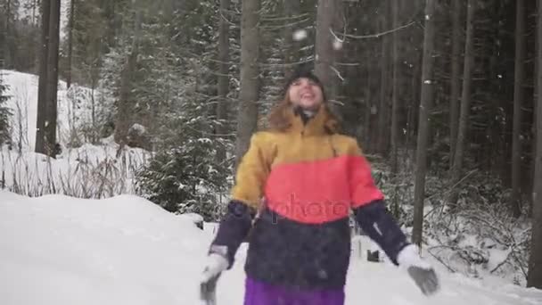 Felice ragazza carina che gioca con la neve all'aperto, vomitando con le mani, bella donna sorridente con le braccia alzate, giovane adolescente femmina in cappotto colorato, vacanze invernali di Natale — Video Stock