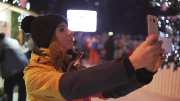 크리스마스 시장에 휴대폰으로 사진을 복용 하는 젊은 여자 — 비디오