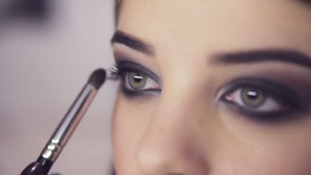 Maquillaje artista la aplicación de maquillaje sombra de ojos a los modelos de ojo. Vista de cerca. Ojos humeantes. Vista derecha — Vídeos de Stock