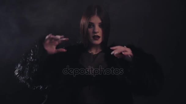 Jovem mulher sexy em vestir casaco de pele preta e reajustar o cabelo. Estúdio com fumo — Vídeo de Stock