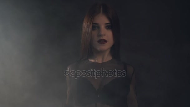 Young sexy woman in putting on black fur coat and readjust her hair. Studio with haze — Stock Video