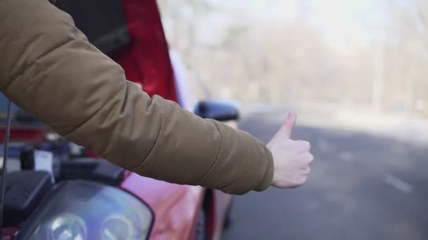 De cerca la mano de un hombre haciendo autostop en una carretera con su coche averiado cerca de él — Vídeo de stock