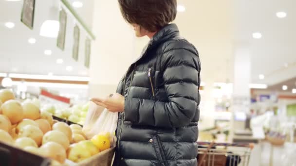 Молода жінка купує в продуктових соусах апельсини — стокове відео