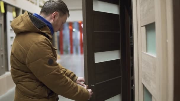 Man in hardware store chosing a door checking a lock — Stock Video