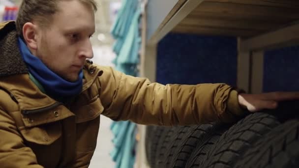 Mann wählt neue Reifen im Geschäft aus und zählt sie — Stockvideo