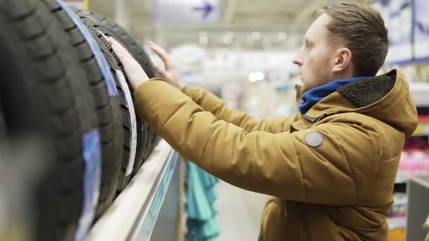 Homem escolhendo pneus novos na loja — Vídeo de Stock