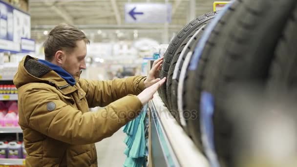 Homme choisissant des pneus neufs en magasin — Video