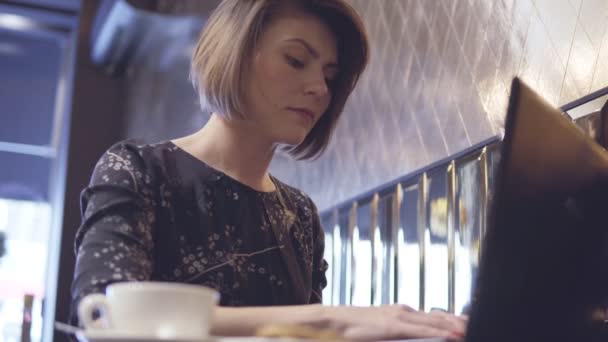 Mujer trabajando en su portátil y disfrutando de su café — Vídeos de Stock