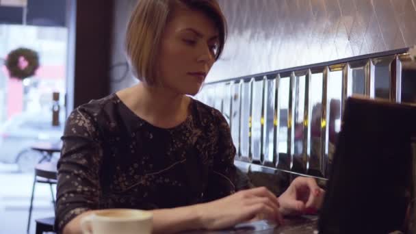 Mujer trabajando en su portátil y disfrutando de su café — Vídeos de Stock