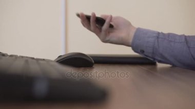 Eller orta bir yetişkin adam akıllı cep telefonu çalışma evinde oturan kullanarak bilgisayar ve klavye yakın:.