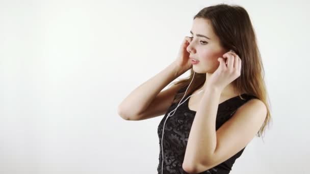 Mulher com fones de ouvido dançando no fundo branco — Vídeo de Stock