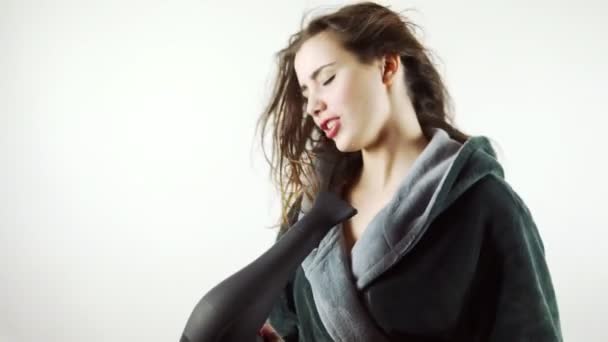 Filmaufnahmen der schönen jungen Frau, die am Föhn singt, isoliert auf weißem Hintergrund — Stockvideo