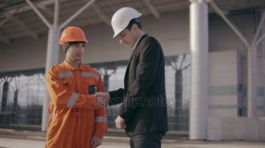 İnşaat işçisi üniformalı bir zarfla para rüşvet vererek elbiseli adam. Mutlu işçi gizleme para. Yolsuzluk anlaşma. Slowmotion