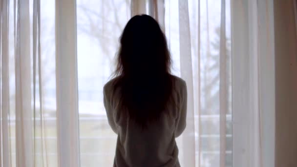 Young woman in sleeping costume opening the curtains in the morning at home — Stock Video