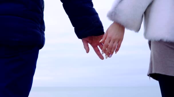 Casal jovem de mãos dadas na praia. Mar e céu ao fundo — Vídeo de Stock