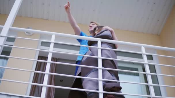 Mladý pár všeobjímající stoje na balkoně — Stock video