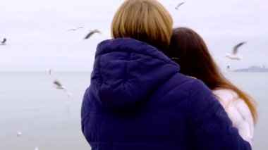 Genç deniz kumsalda çift. Çift sahilde sarılma ve el ele tutuşarak seviyorum. Arka plan uçan martılar