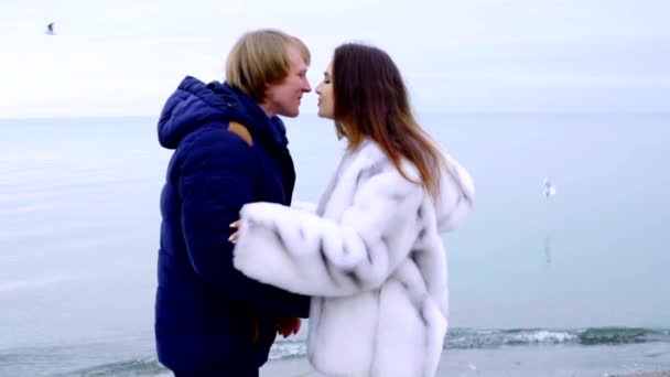 Gelukkige paar omhelzen en spinnen rond door de zee, slow-motion shot. Liefde concept, jonge gezin tijd samen doorbrengen, genieten van de prachtige natuur. Knuffel man en vrouw verheffen, staan en draai rond — Stockvideo