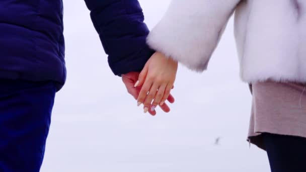 Jong koppel hand in hand op het strand. Zee en de lucht op de achtergrond — Stockvideo