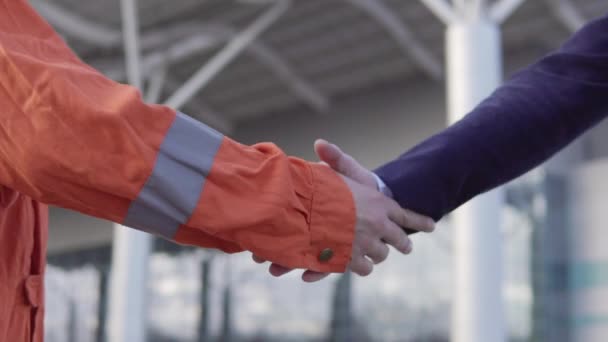 Trabajador profesional en uniforme naranja estrechando la mano con el hombre de negocios en un traje. Vista de cerca — Vídeos de Stock