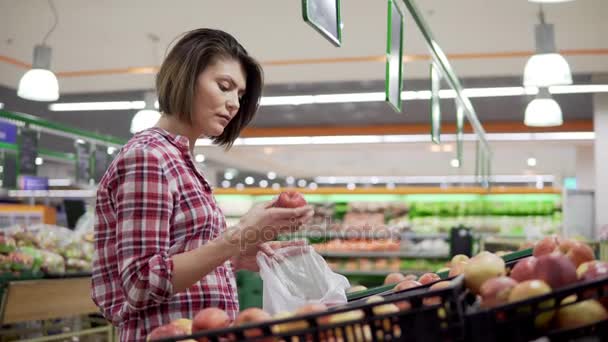 Hermosa mujer de compras manzanas rojas en el supermercado — Vídeo de stock