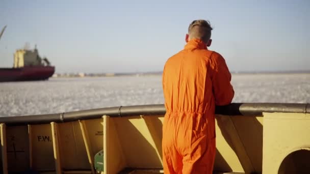 Junger Mann in orangefarbener Uniform im Winter an Bord des Schiffes. — Stockvideo
