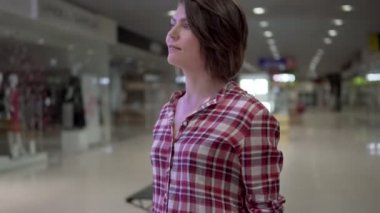 Genç güzel esmer kadın yakınındaki dükkanlardan alışveriş alışveriş merkezinde yürüyen bir gömlek