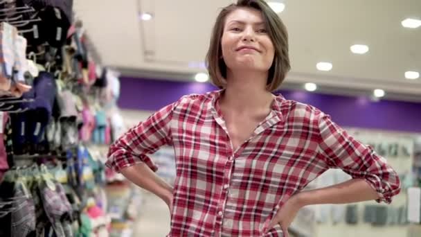 Όμορφη νεαρή γυναίκα ψώνια σε ένα σούπερ μάρκετ που προσπαθεί να επιλέξετε κάτι. Κάνοντας ένα διάλειμμα ή παύση. Προσπαθώντας να συμβουλευτείτε κάποιον. Δύσκολη επιλογή. — Αρχείο Βίντεο