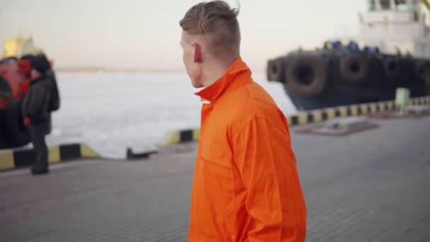 Hafenarbeiter in orangefarbener Uniform läuft im Hafen und kontrolliert den Arbeitsprozess im Hafen. — Stockvideo