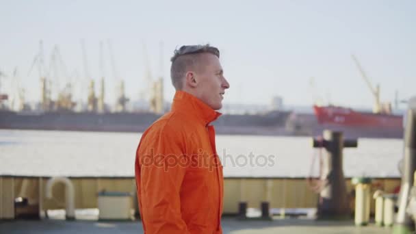 Trabalhador portuário em uniforme laranja está andando no local do porto de carga. Movimento lento — Vídeo de Stock