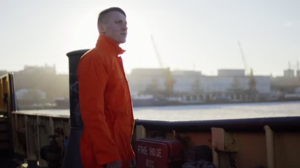 Λιμάνι εργαζόμενος σε πορτοκαλί στολή στέκεται από το Διοικητικό Συμβούλιο του πλοίου. Αναλαμπή φακού. Slowmotion — Αρχείο Βίντεο
