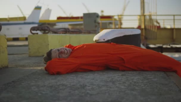 Portret van de jonge werknemer in oranje uniforme rusten tijdens zijn doorbraak door de zee — Stockvideo