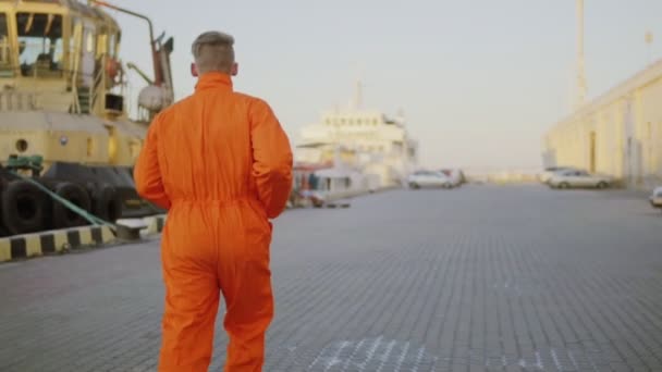 Arbeiter in orangefarbener Uniform läuft im Hafen — Stockvideo