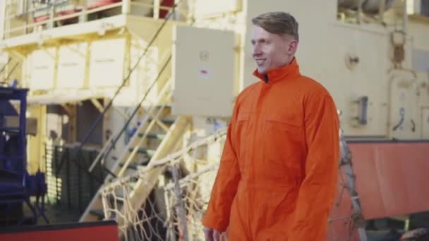 Trabajador del puerto en uniforme naranja está caminando en el sitio del puerto de carga. Lento. — Vídeos de Stock