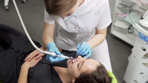 Giovane dentista femminile in guanti e maschera perforazione denti pazienti in clinica — Video Stock