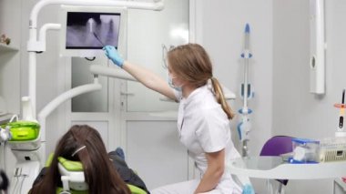 Sağlıklı dişler ve diş sağlık. Kendine güvenen profesyonel doktor diş hekimi x-ray diş bir tablete gösteriyor. Maske ve laboratuvar ceket Bayan diş hekimi.