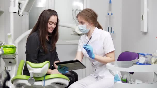 Dentes saudáveis e saúde dentária. Médico dentista profissional confiante está mostrando dentes de raios-X em um comprimido. Dentista feminina em máscara e jaleco . — Vídeo de Stock