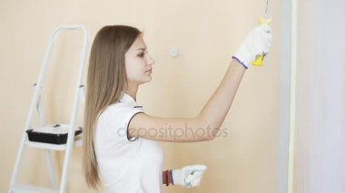 Genç çift beyaz gömlek içinde yeni evlerinin süsleyin. Genç karı koca boya merdaneleri kullanarak duvar boya vardır. Güzel çift onların yeni ev onarım yapma.