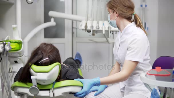 Dentist chair raises up with patient. Young female dentist pushes button to raise dental chair up with patient. — Stock Video