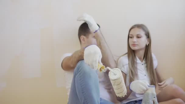 Genç çift tadilatı ve boya silindirleri ve fırçalar ile katta oturan bir mola — Stok video